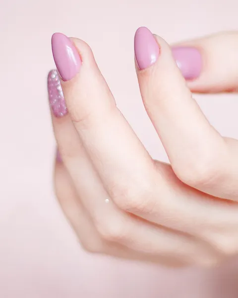 Mão com unhas amendoadas esmaltadas de rosa